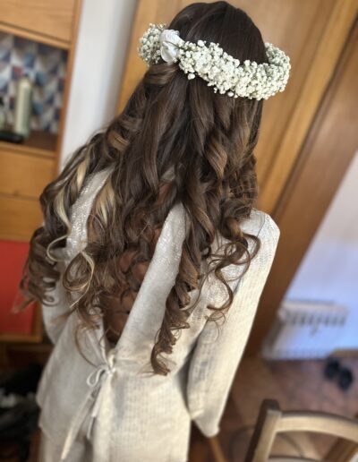 Acconciatura sposta capelli lunghi con coroncina di fiori.